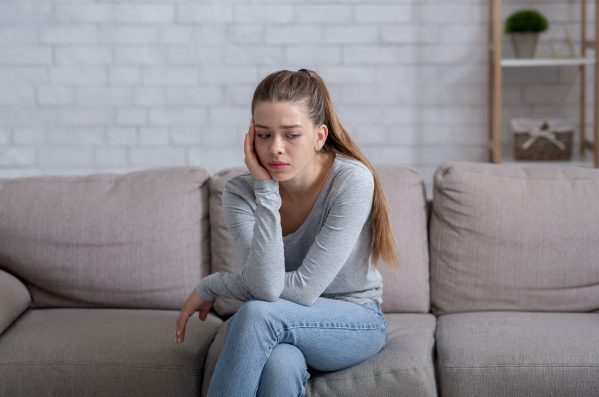 Mental health concept. Young woman having depression on sofa at home