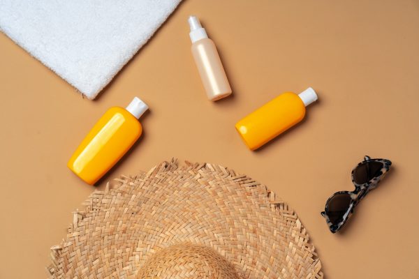 Suntan cosmetic product with towel, hat and sunglasses