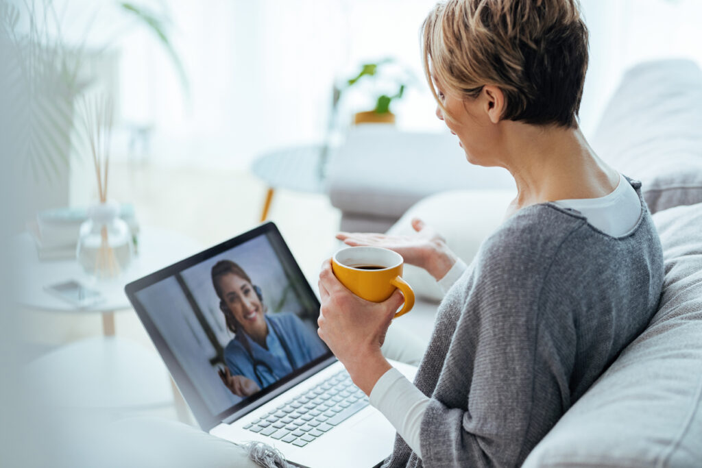 Woman sitting on the sofa while making a private video call over laptop with her doctor. All from the comfort of her home.